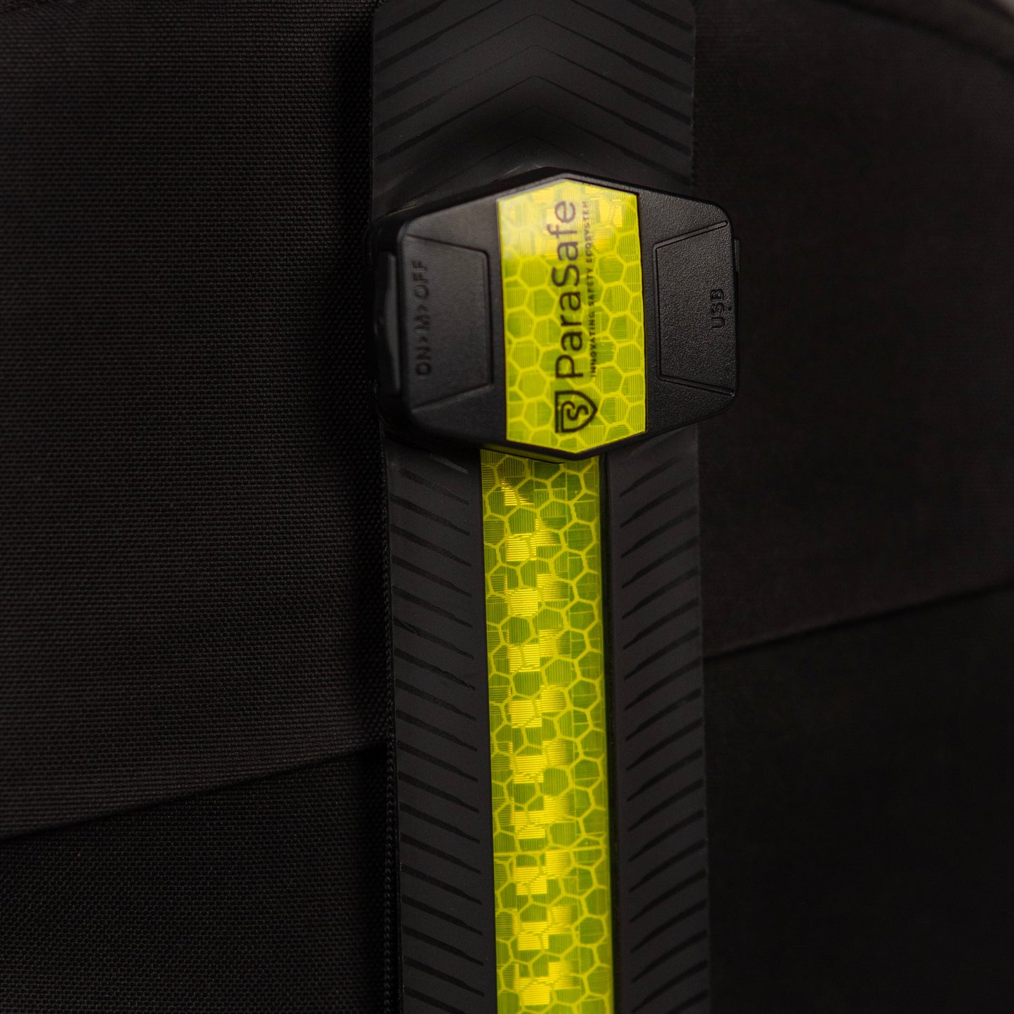 Close-up of a black backpack with a green ParaSafe reflective strip featuring a logo.