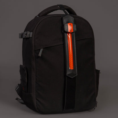 Black backpack with red ParaSafe LED wearable strip a gray background